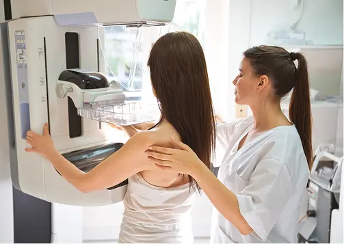 A healthcare professional assists a patient during a mammogram procedure, demonstrating the use of advanced imaging technology for breast health screening.
